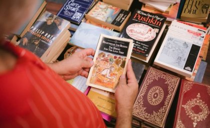 Woman holding old book with other books in background at Book Fair.